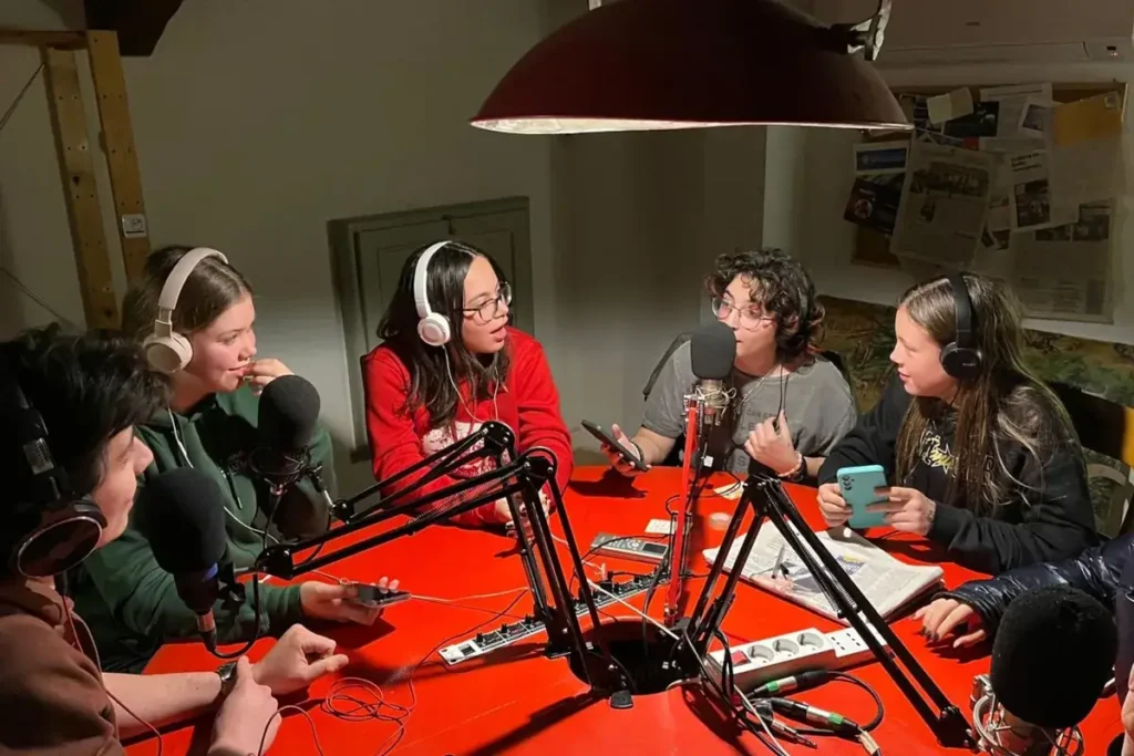 Ragazze e ragazzi di Radioimmaginaria al tavolo di regia con microfoni e cuffie